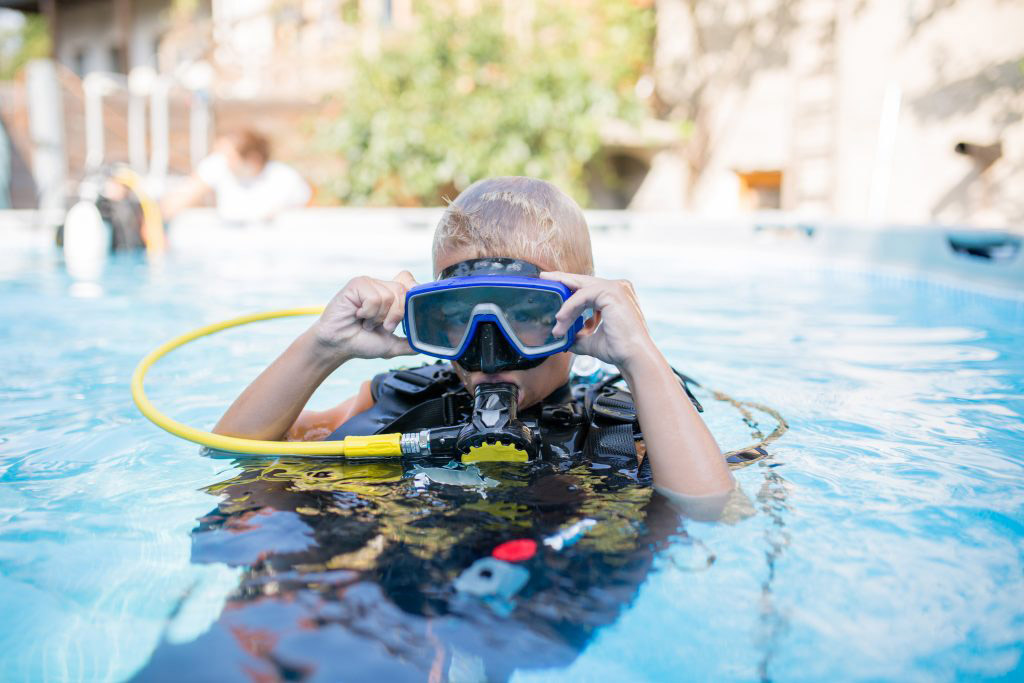 Young child in the pool wearing scuba gear